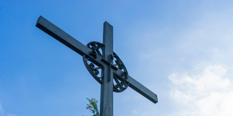 Una croce in uno sfondo con cielo e nuvole