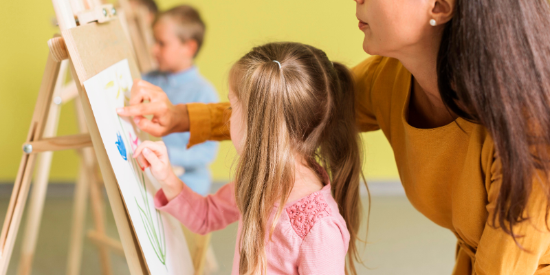 bambina che dipinge con la maestra