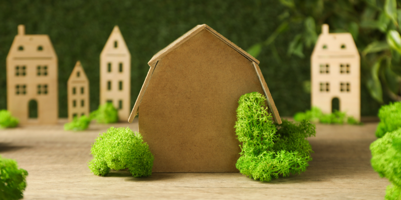 Riproduzione in cartone di una casa con dell'erba verde intorno