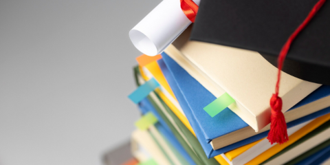 Libri impilati, un cappello di laurea e un diploma